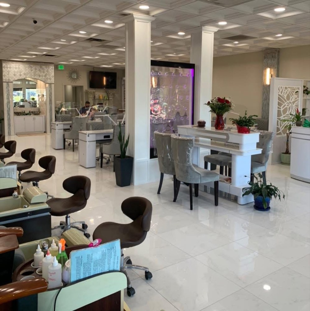 Inside Oasis Nail Spa — white marble floors, columns, silver-grey velvet chairs, and the purple bubble water feature wall